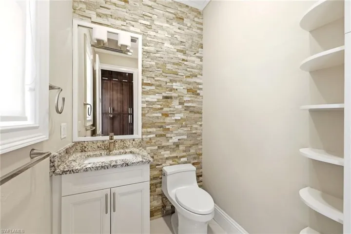 Half bath off kitchen with extra shelving and extensive stonework
