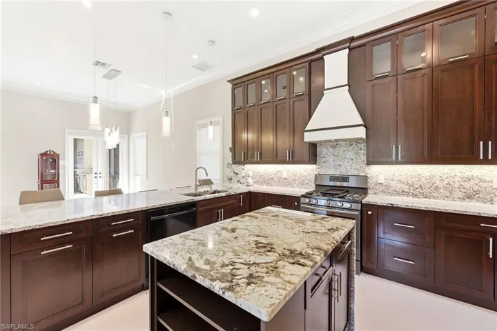 View of kitchen island, gas stove and storage space