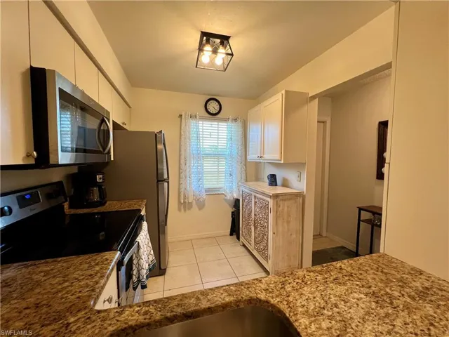Kitchen featuring light tile patterned flooring, stainless steel appliances, and white cabinets