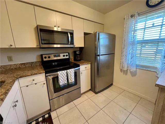 Kitchen featuring white cabinetry, appliances with stainless steel finishes, a healthy amount of sunlight, and light tile patterned flooring