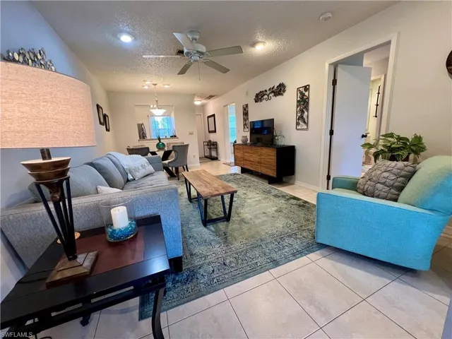 Tiled living room with ceiling fan and a textured ceiling