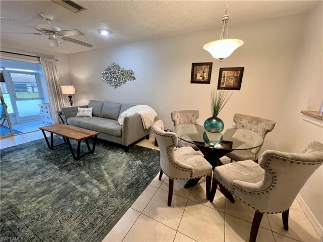 Dining area with ceiling fan, light tile patterned floors, and a textured ceiling