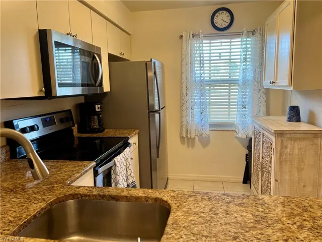 Kitchen featuring stainless steel appliances, white cabinetry, sink, and light tile patterned flooring