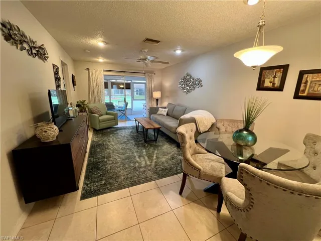 Living room featuring light tile patterned floors, a textured ceiling, and ceiling fan