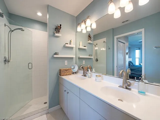 Bathroom featuring ensuite bathroom, double vanity, a stall shower, and light tile patterned floors