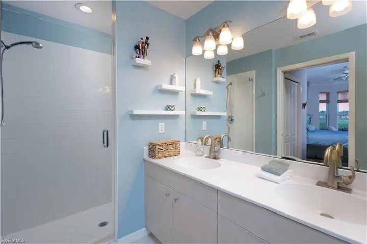 Full bath featuring double vanity, ensuite bath, and a shower stall