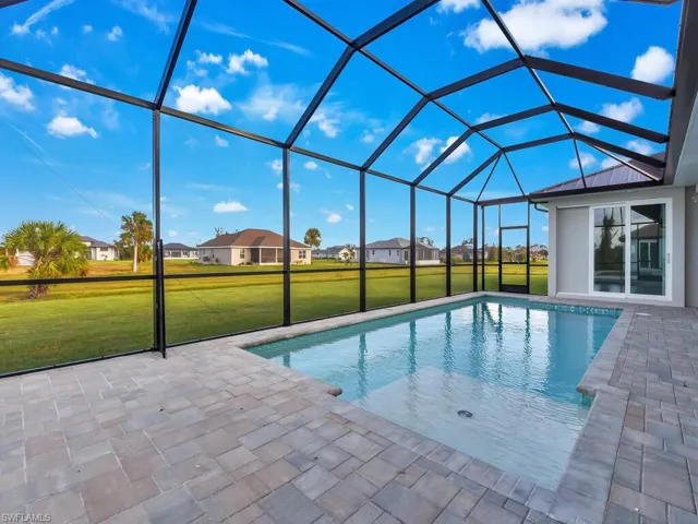 Swimming pool with a lawn, a patio area, and glass enclosure
