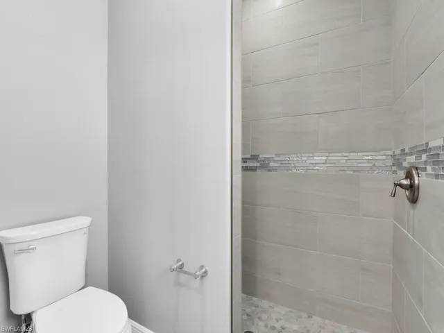 Full bath featuring a tile shower and toilet