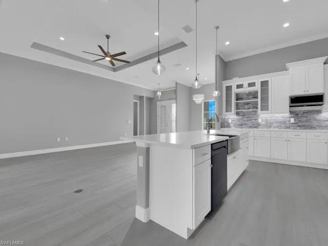 Kitchen with stainless steel microwave, dishwasher, tasteful backsplash, an island with sink, and ceiling fan