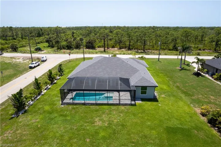 Aerial view of property and surrounding area featuring a heavily wooded area and a pool area