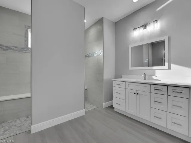 Full bath featuring a walk in shower, vanity, wood finished floors, and recessed lighting