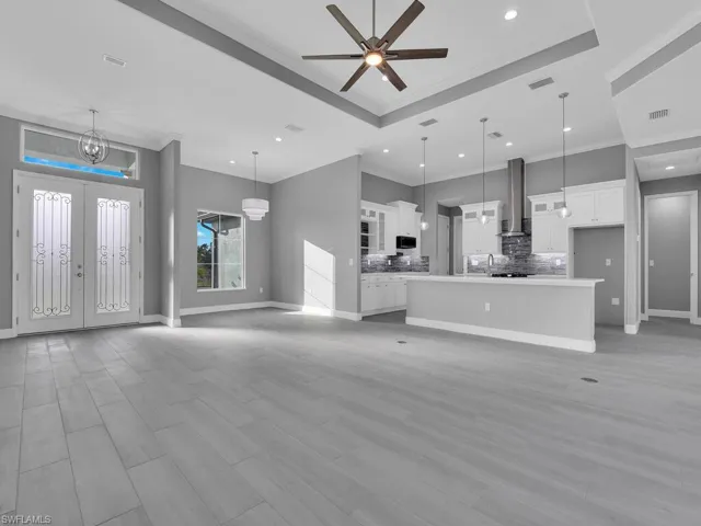 Unfurnished living room with ornamental molding, recessed lighting, light wood finished floors, a chandelier, and a ceiling fan