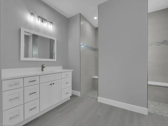 Bathroom with walk in shower, vanity, wood finished floors, and recessed lighting