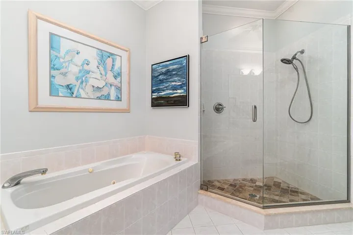 Full bath featuring a jetted tub, a shower stall, ornamental molding, and tile patterned flooring