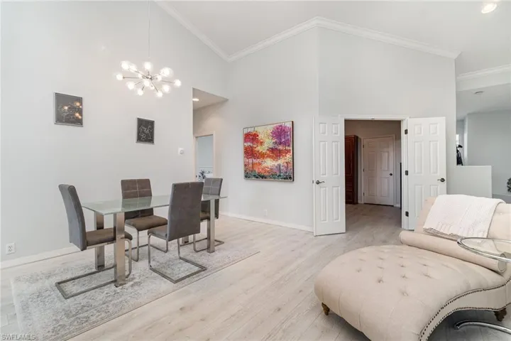 Dining area featuring light wood-style floors, crown molding, chandelier, and high vaulted ceiling