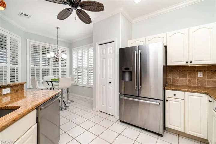 Kitchen featuring tasteful backsplash, appliances with stainless steel finishes, crown molding, and light tile patterned flooring