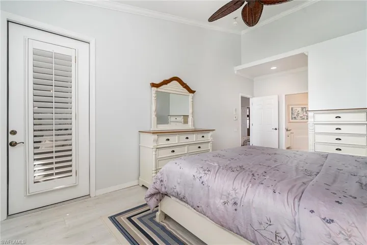 Master bedroom featuring crown molding, light wood-style flooring, ensuite bathroom, ceiling fan, and direct lanai access