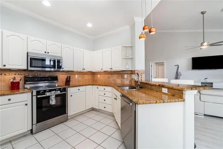 Kitchen with Bosch stainless steel appliances, open floor plan, stone countertops, and a peninsula