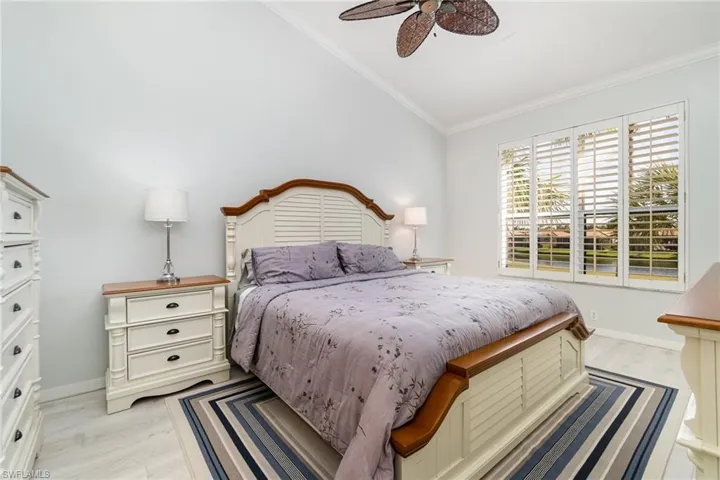 Master bedroom with light wood-style flooring, ceiling fan, vaulted ceiling, and crown molding