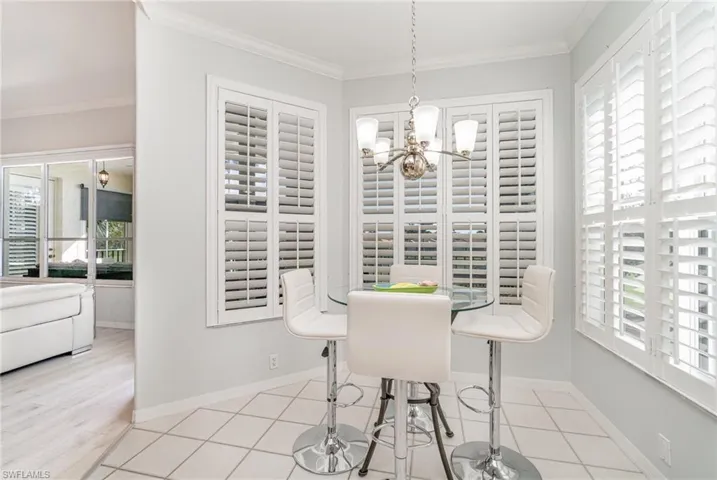 Tiled dining area with a chandelier, a wealth of natural light and crown molding