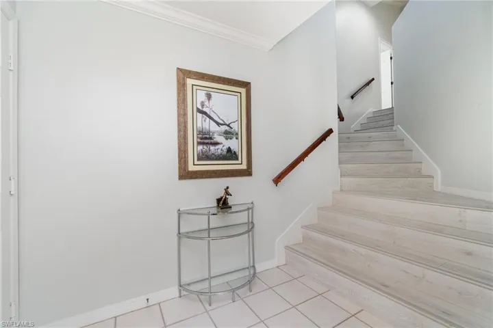 Stairs featuring baseboards, crown molding, and tile patterned floors