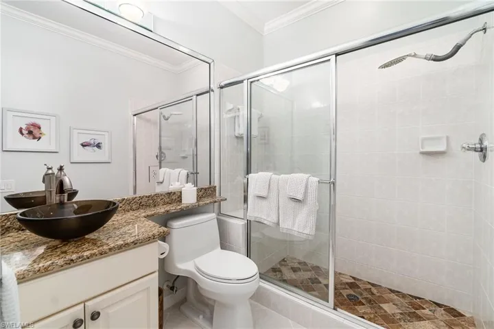 Guest bathroom with crown molding, a shower stall and vessel sink