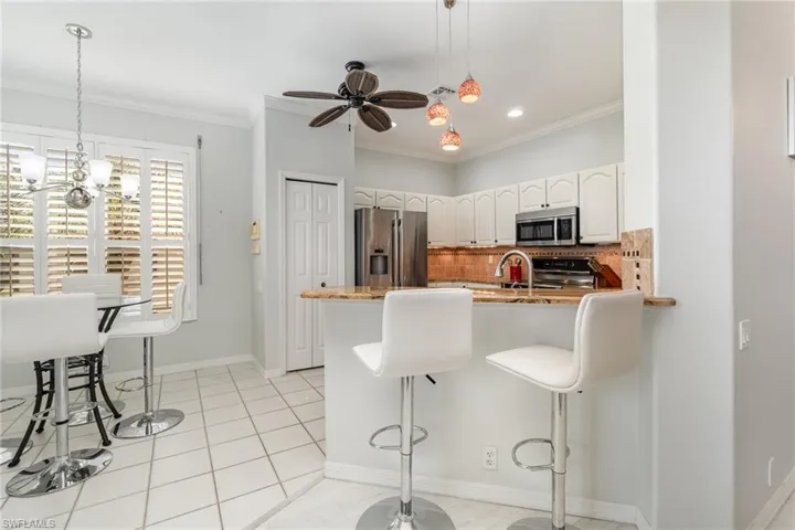 Kitchen featuring a breakfast bar area, appliances with stainless steel finishes, a peninsula, and crown molding