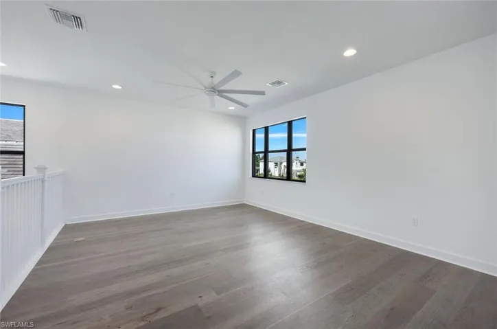 Loft area with ceiling fan and dark wood-type flooring