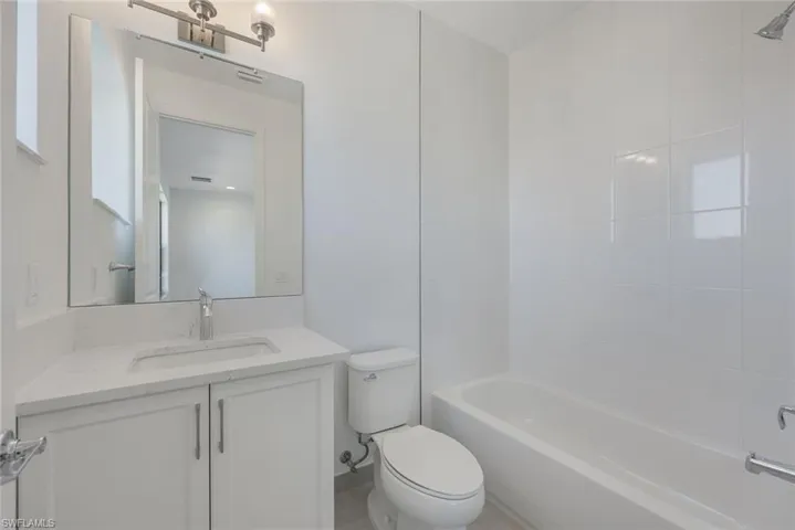 Full bathroom with tiled shower / bath, vanity, and toilet