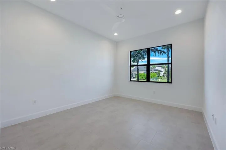 Den with light tile patterned floors and ceiling fan