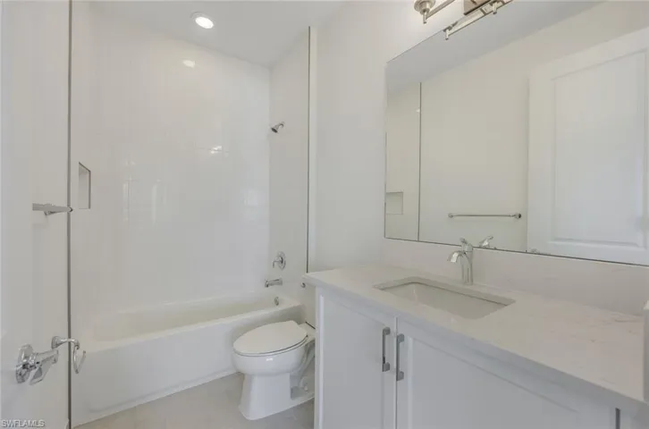 Full bathroom with tile patterned floors, tiled shower / bath, vanity, and toilet