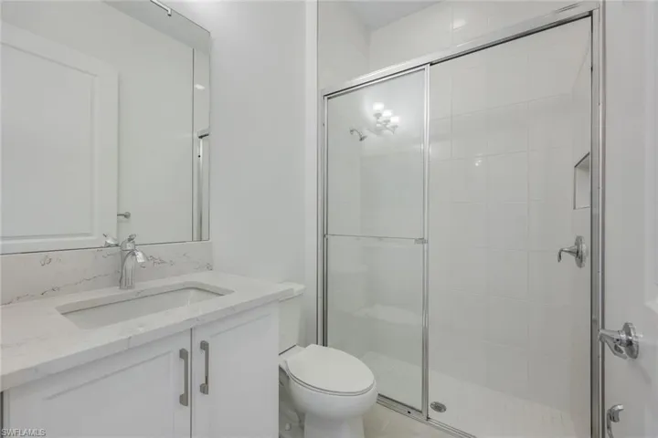 Bathroom featuring vanity, an enclosed shower, and toilet