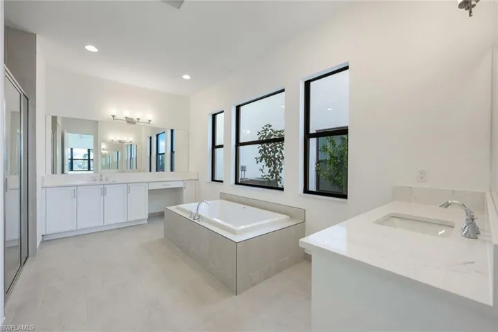 Primary Bathroom featuring shower with separate bathtub and his/her vanities