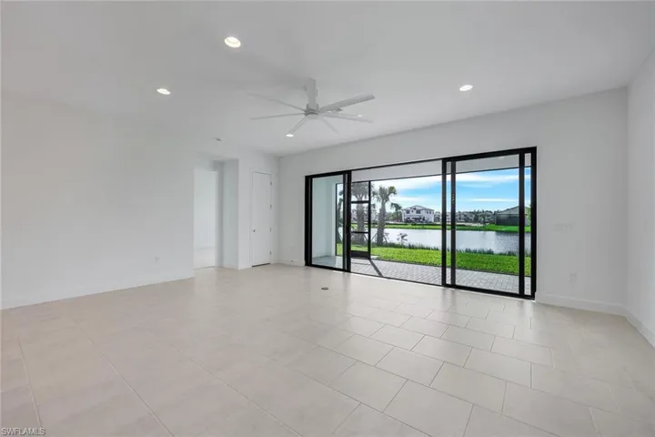 Living room with a water view, ceiling fan, and light tile patterned floors
