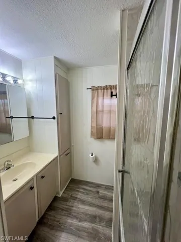 Bathroom with a stall shower, wood finished floors, vanity, and a textured ceiling