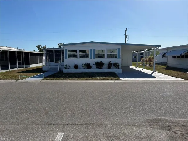 Manufactured / mobile home with a carport, a sunroom, and driveway