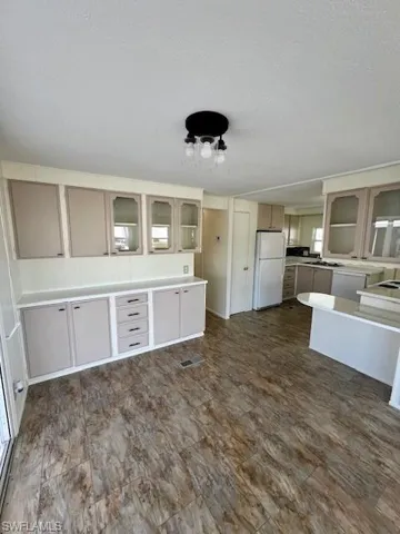 Kitchen with glass insert cabinets, a textured ceiling, freestanding refrigerator, visible vents, and a sink