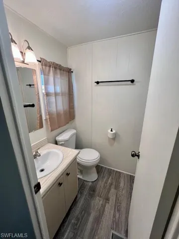Bathroom featuring vanity, a textured ceiling, toilet, visible vents, and wood finished floors