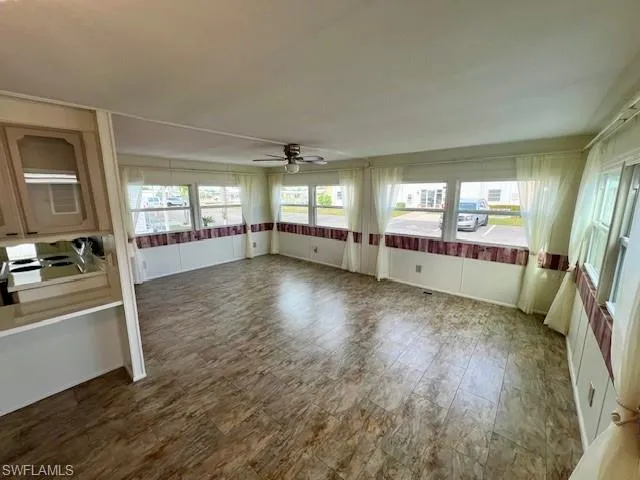 Unfurnished sunroom with wood finished floors and ceiling fan