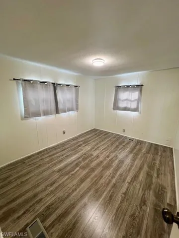 Unfurnished room featuring visible vents, wood finished floors, and a textured ceiling