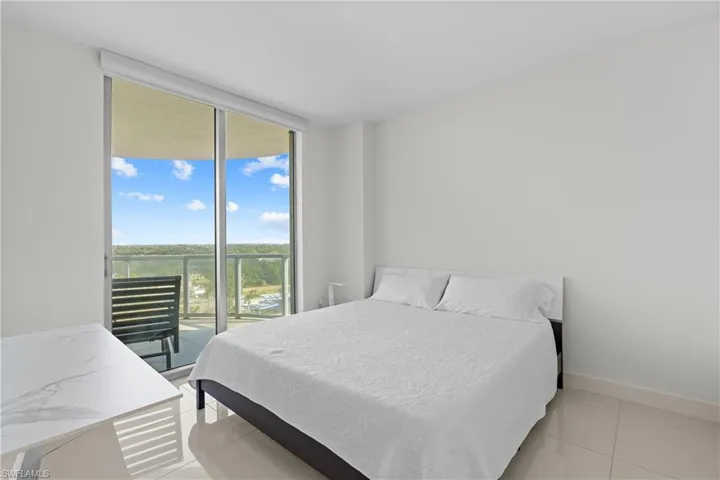 Bedroom featuring expansive windows, access to outside, and light tile patterned flooring