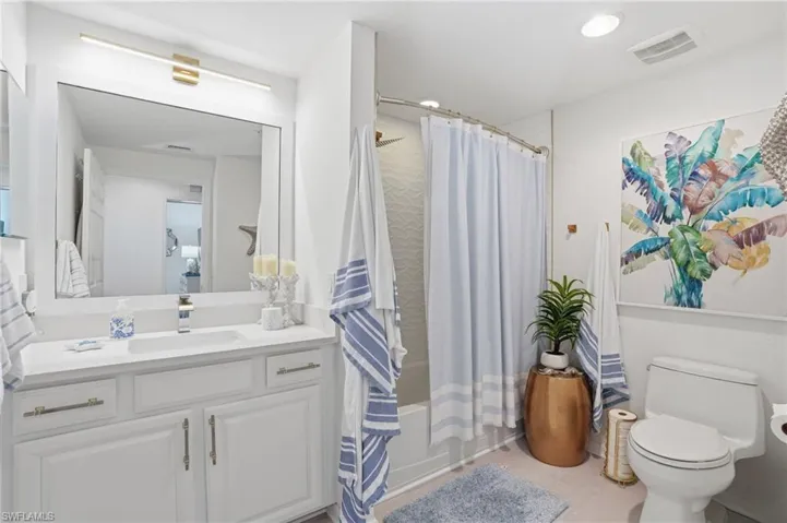 Bathroom featuring a white vanity with an integrated sink, polished chrome faucet, and gold-tone hardware