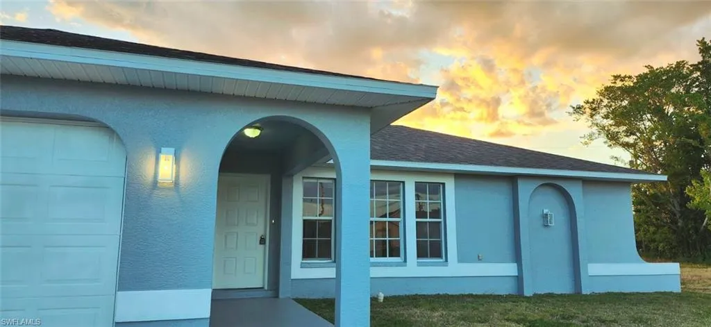 Exterior entry at dusk with a garage and a yard