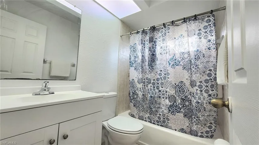 Full bathroom featuring shower / bath combination with curtain, toilet, and vanity