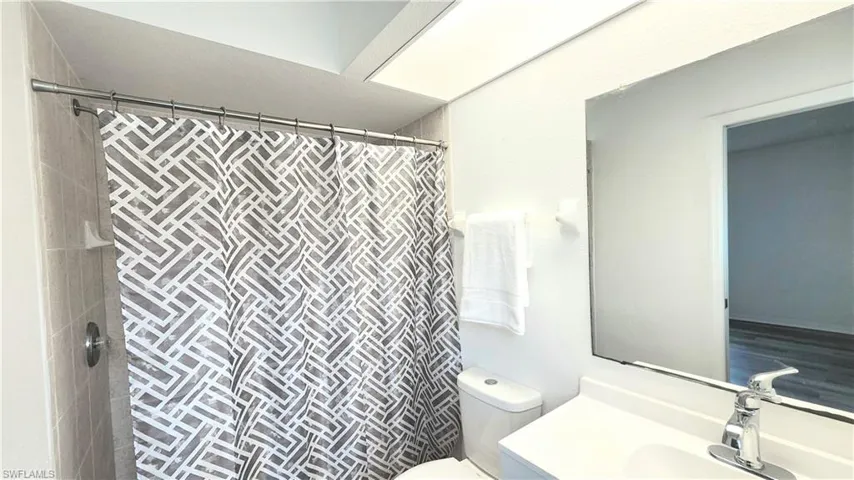 New vanity and sink, natural light from a window with fogged glass, shower behind curtain