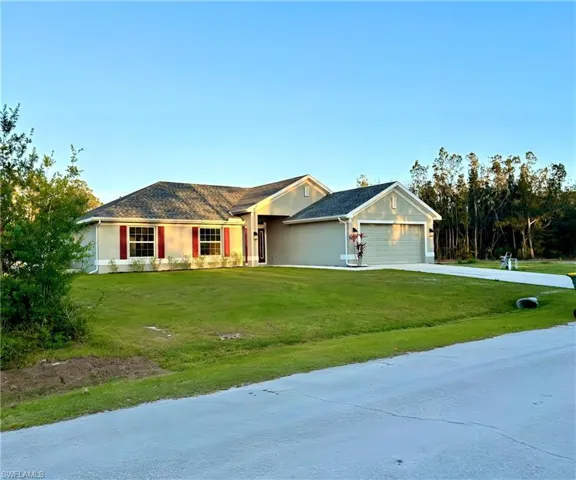 Ranch-style house featuring driveway, stucco siding, a front yard, and an attached garage