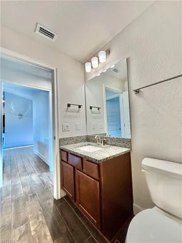 2nd Bathroom featuring a textured wall, visible vents, toilet, and vanity