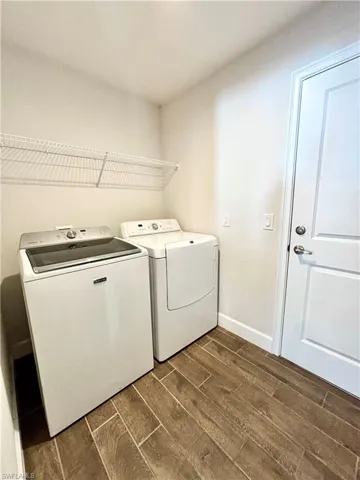 Laundry room featuring baseboards, washing machine and dryer, laundry area, and wood finish  tile floors