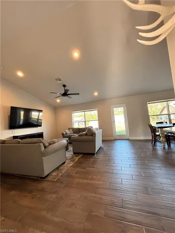 Living room with dark wood-type tile flooring, lofted ceiling, ceiling fan, and recessed lighting