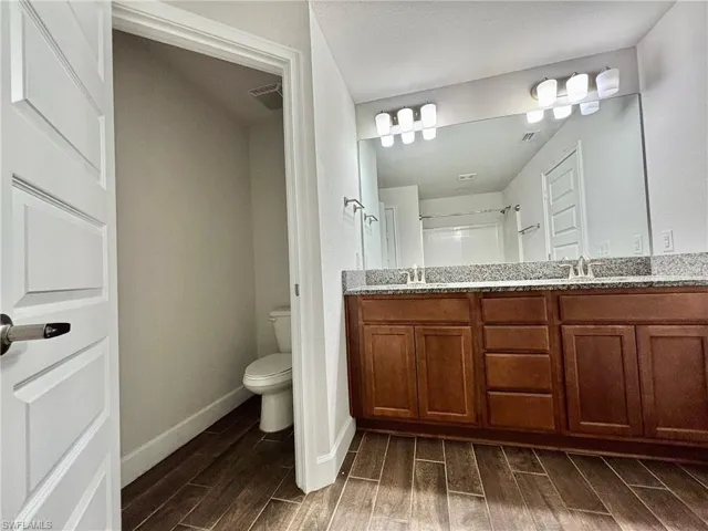 Master  bathroom featuring toilet, a sink, double vanity, and wood tiled floor